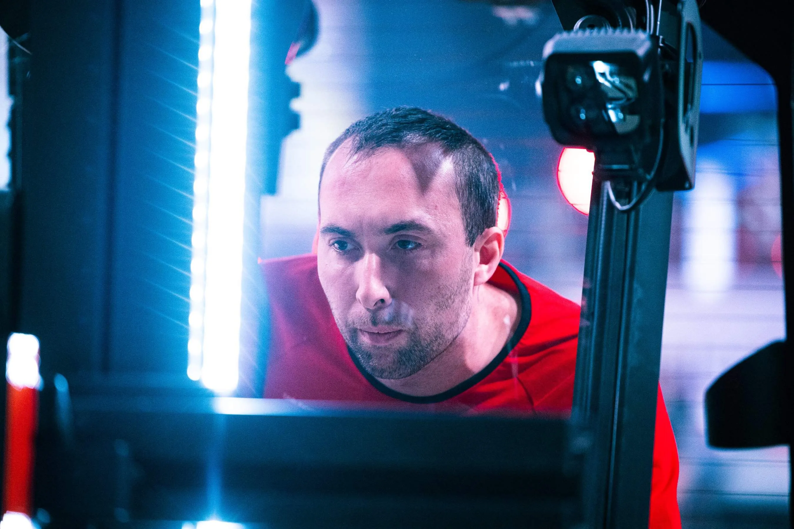 A driver with a concentrated look, seen through a frame of blue and red light