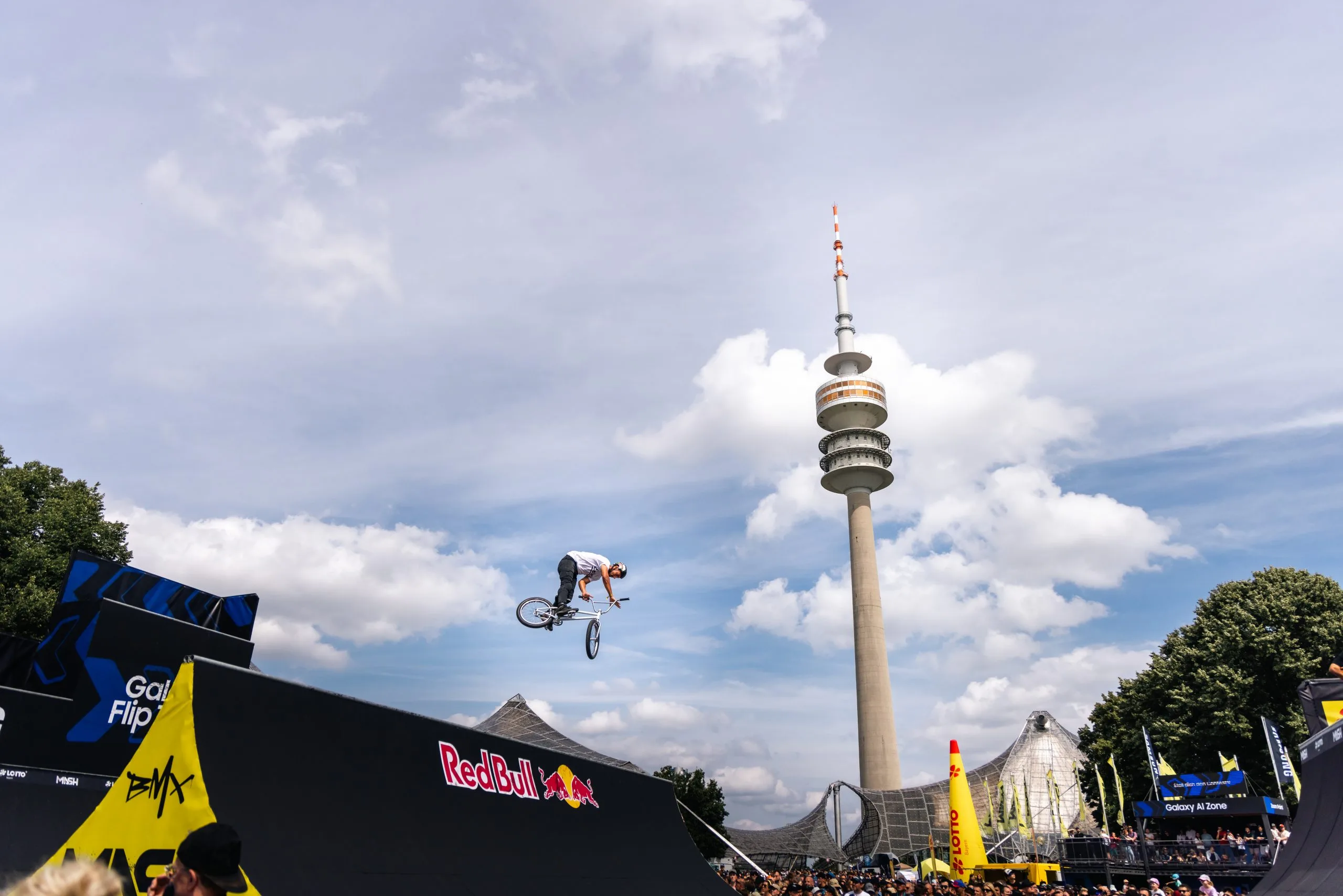 A BMX rider in mid-air in front of the Olympic Tower in Munich