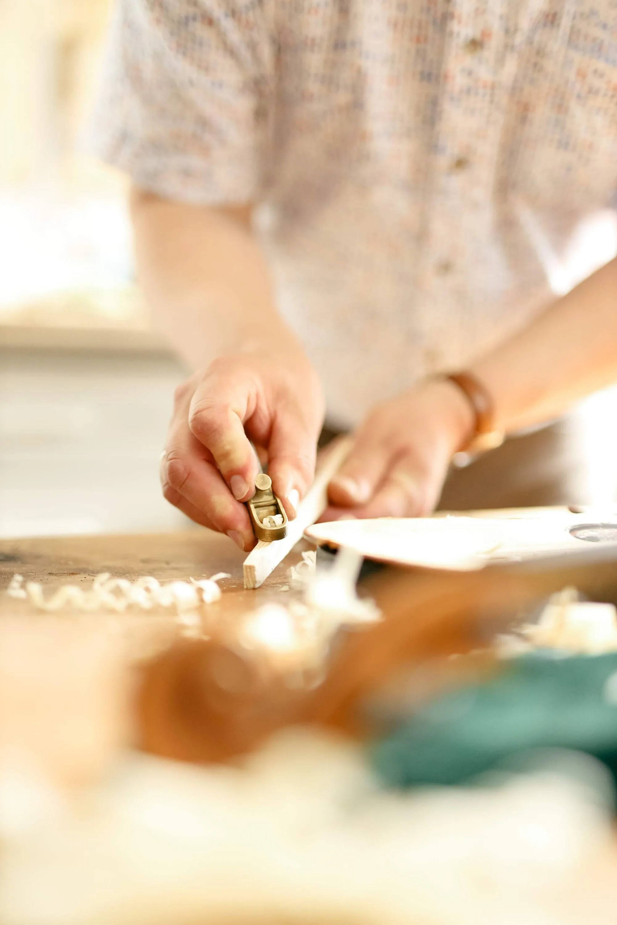 Hands of a violin maker shaping a piece of wood with a small brass plane