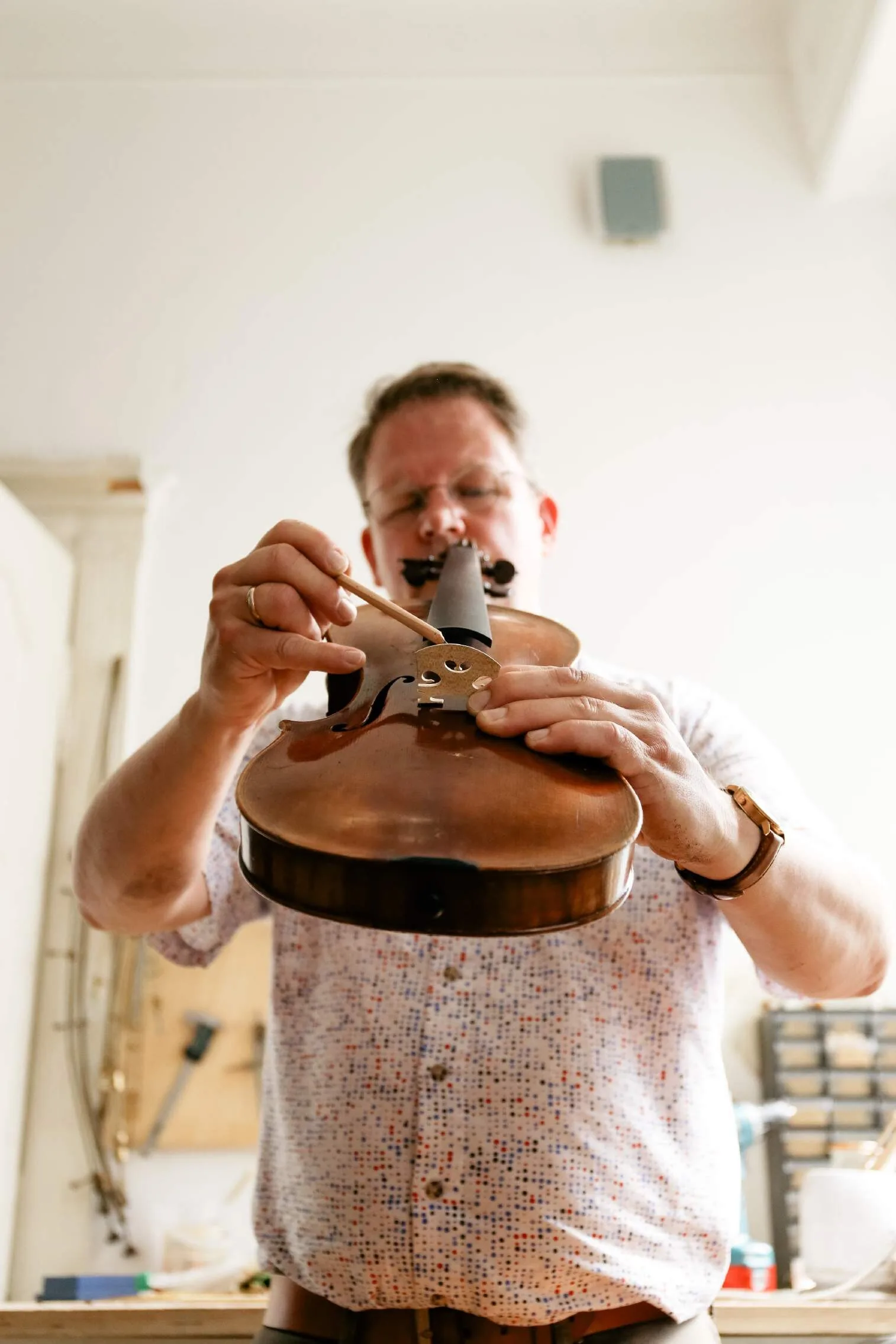 The violin maker adjusting the sound post inside a violin