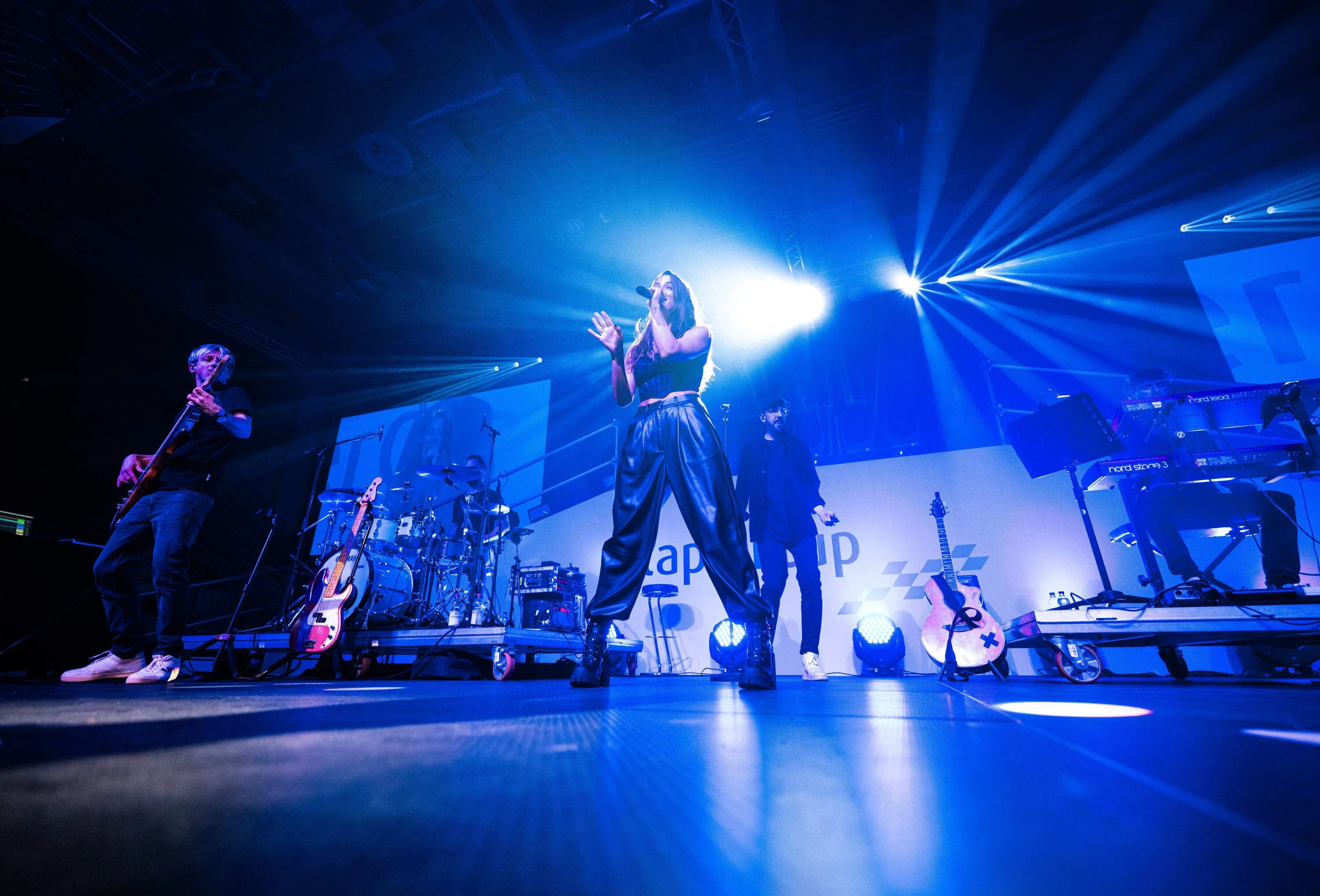 A singer on stage in blue light with a band behind her